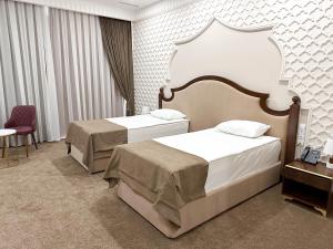 a hotel room with two beds and a table at Reikartz Sote Tashkent in Tashkent