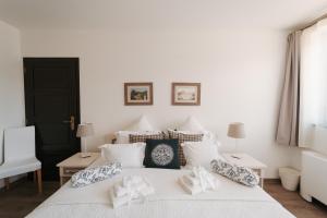 a bedroom with a white bed with pillows on it at Rókusfalvy Borhotel és Fogadó in Etyek