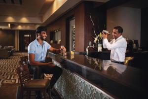 Zwei Männer sitzen an einer Bar und trinken Wein. in der Unterkunft Movenpick Waterpark Resort & Spa Soma Bay in Hurghada