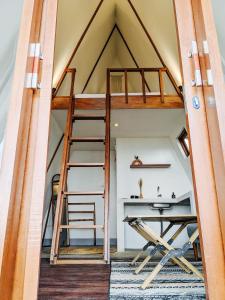 Cama elevada en habitación con escritorio y escalera en PukuPods - Tent & Cabin, en Tabanan