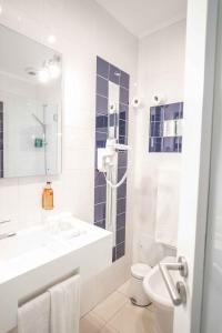 a white bathroom with a sink and a toilet at Grande Pensao Residencial Alcobia in Lisbon