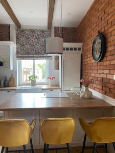 a kitchen with yellow chairs and a brick wall at Anny Łajming 2D in Słupsk