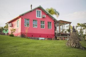 una casa roja sentada en la parte superior de un exuberante campo verde en Cabana Vêneto na Serra Gaúcha próx á Bento Gonçalves, en Cotiporã
