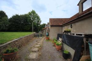 a house with potted plants next to a wall at A nicely presented friendly comfortable cottage in Thornbury