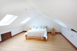 a white bedroom with a bed in a attic at A nicely presented friendly comfortable cottage in Thornbury