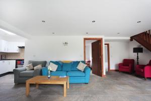 a living room with a blue couch and red chairs at A nicely presented friendly comfortable ECO cottage in Thornbury