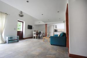 a living room with a blue couch and a kitchen at A nicely presented friendly comfortable cottage in Thornbury