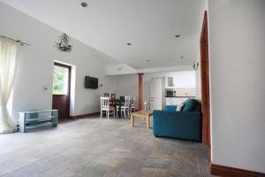 a living room with a blue couch and a kitchen at A nicely presented friendly comfortable ECO cottage in Thornbury