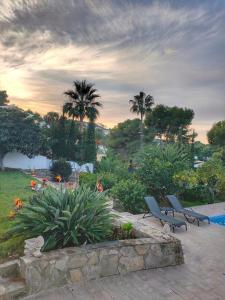 a garden with two chairs and flowers and palm trees at Apartments in a "VILLA VISTA JAVEA" in Jávea