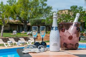 una botella de vino y copas en una mesa cerca de una piscina en Outstanding Finca RÚSTICA FELOSTAL with Sauna&Pool, en Son Ferriol