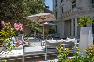 a patio with chairs and a table with an umbrella at Le Champlain in La Rochelle