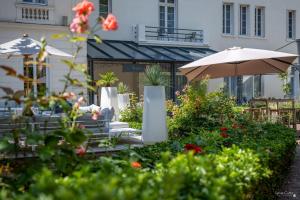 a patio with chairs and an umbrella and flowers at Le Champlain in La Rochelle