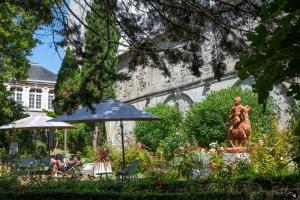 a garden with a statue and an umbrella and people at Le Champlain in La Rochelle