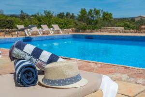 kapelusz i szalik siedzący obok basenu w obiekcie Outstanding Finca RÚSTICA FELOSTAL with Sauna&Pool w mieście Son Ferriol