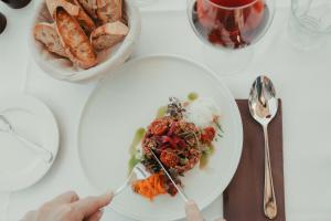 een persoon die een bord eten op een tafel bij Rókusfalvy Borhotel és Fogadó in Etyek