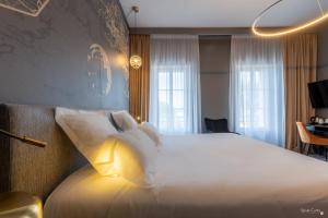 a hotel room with a large bed with white pillows at Le Champlain in La Rochelle