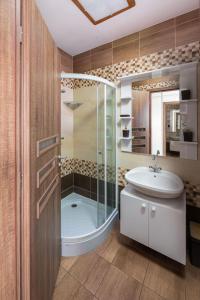 a bathroom with a glass shower and a sink at Art Apartments in Hajdúszoboszló