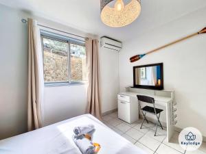 um quarto com uma cama, uma secretária e uma televisão em Ti Paradis, 3 etoiles à deux pas du centre de Saint-Gilles em Saint-Gilles-les-Bains