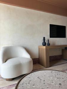 a living room with a white chair and a tv at Igisó in Ermoupoli
