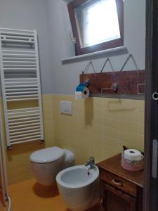 ein Bad mit einem WC, einem Waschbecken und einem Fenster in der Unterkunft Da antonella in Cerretto Langhe