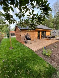 een huis met een houten terras in een tuin bij Chalet Liquidambar in Zutendaal