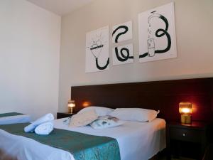 1 dormitorio con 2 camas y 2 cuadros en la pared en My Friend Antonia, en Barcellona-Pozzo di Gotto
