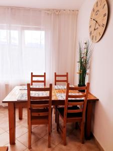 a dining room table with chairs and a clock on the wall at Apartmán Terminál, self check-in 24 h in Banská Bystrica