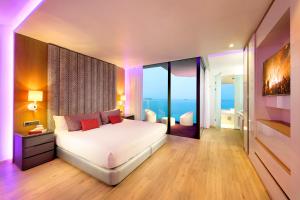 a bedroom with a white bed with a view of the ocean at Hard Rock Hotel Ibiza in Playa d'en Bossa