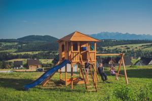 a couple of people standing next to a playground at Dziewięćsił &Chaber _domki blisko lasu in Grywałd
