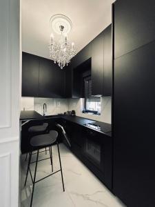 een zwarte keuken met een stoel en een kroonluchter bij Apartment Talija in Trebinje
