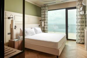 a hotel room with a bed and a balcony at Maximilian Suites in Trieste