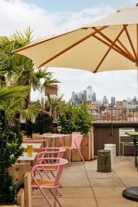 eine Terrasse mit rosa Stühlen und einem Sonnenschirm in der Unterkunft Kingsland Locke in London