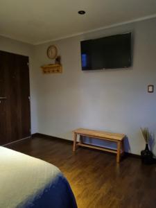 a bedroom with a table and a flat screen tv on the wall at LengaUsh in Ushuaia