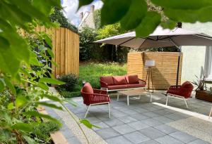 a patio with a couch and chairs and an umbrella at Hôtel Villa Berlioz in Lyon