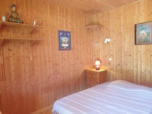 a bedroom with a bed and a wooden wall at Domaine d'Avallon - petit Tibet au coeur des Alpes in Arvillard
