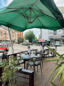 un grupo de mesas y sillas bajo una sombrilla verde en Hotel LaCorte Prishtina en Pristina
