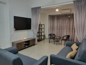 a living room with a blue couch and a flat screen tv at Manjung CY Homey Stays The Venus Residence in Seri Manjung