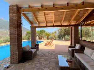 a patio with a wooden pergola next to a pool at Harmony Home in Alcaucín