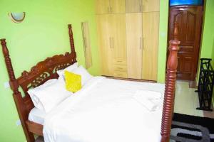 a bedroom with a wooden bed with a yellow pillow at Exquisite 1bedroom located in Garden Estate, Thome in Nairobi