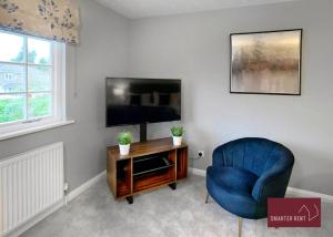 uma sala de estar com uma cadeira azul e uma televisão em Weybridge - 4 Bedroom Home - Driveway & Garden em Walton-on-Thames