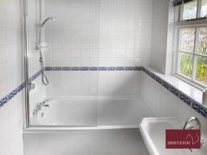 a white bathroom with a tub and a sink at Weybridge - 4 Bedroom Home - Driveway & Garden in Walton-on-Thames