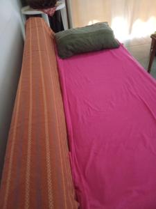 uma cama com lençóis cor-de-rosa e uma almofada verde em Spacious apartment in center of Agia Napa em Agia Napa