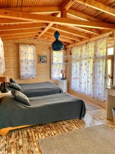 two beds in a room with wooden ceilings and windows at Bamboo Bungalow with Sea View in Kabak Bay, Ölüdeniz in Fethiye