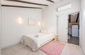 a white bedroom with a white bed and a pink rug at Bohemian 2bedroom attic in Lavapies in Madrid