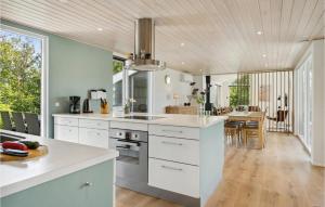 a kitchen with white cabinets and a dining room at Nice Home In Lkken With 4 Bedrooms, Sauna And Wifi in Grønhøj