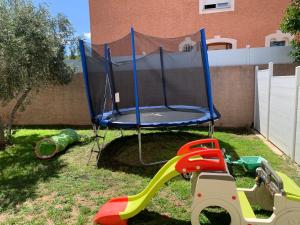 a play set with a trampoline in a yard at Location saisonnière in Béziers