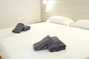 1 cama blanca con 2 almohadas y toallas en MAKĀI Bungalows, en Playa del Águila