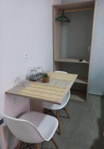 una mesa y 2 sillas blancas en una habitación en Rosa dos ventos suíte 1, en Florianópolis