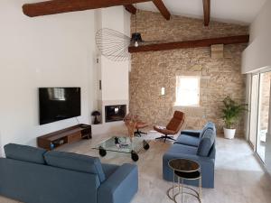 ein Wohnzimmer mit 2 blauen Sofas und einem TV in der Unterkunft Maison de Charme - Maréchalerie - Nîmes in Uchaud
