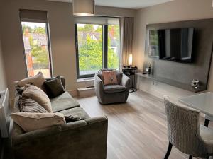 sala de estar con sofá, sillas y TV en Balmoral Apartment on Lisburn Road by Lesley en Belfast